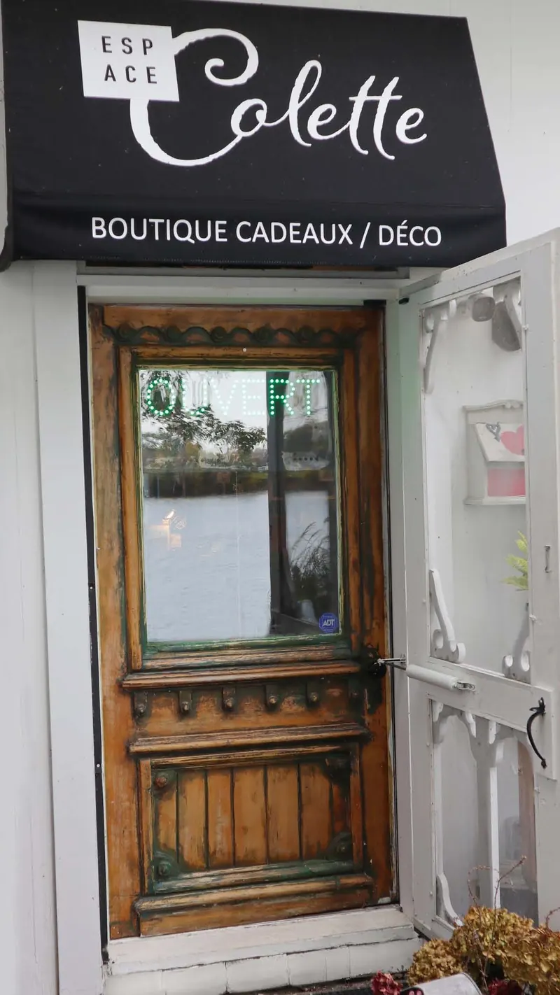 Porte d’entrée ancienne en bois sous l’auvent noir « Espace Colette — Boutique cadeaux / déco », avec l’enseigne « Ouvert » dans la fenêtre