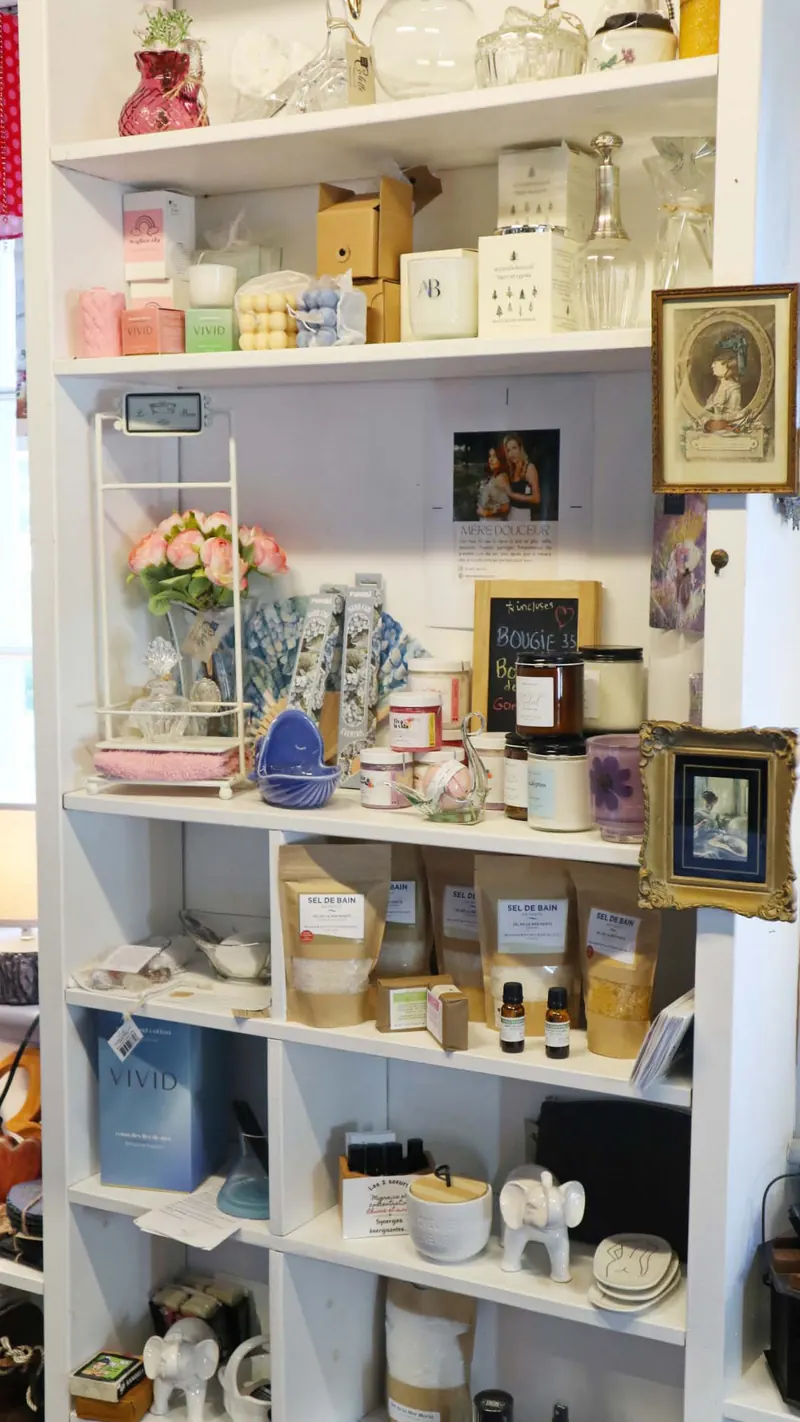 Étagères blanches garnies de chandelles, de sels de bain, de savons et de petits objets déco dans la boutique